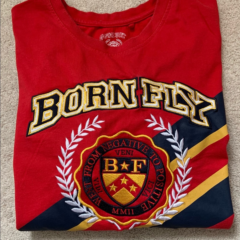 Born Fly. Red with bold Blue, Yellow and Red stripes across the chest.